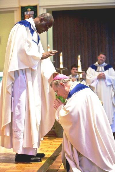 At left, newly ordained, Rev. Fr.Vilaire Philius, bestows his first blessing as a priest on the bishop that ordained him; Most Rev.Thomas Wenski, former Bishop of Orlando